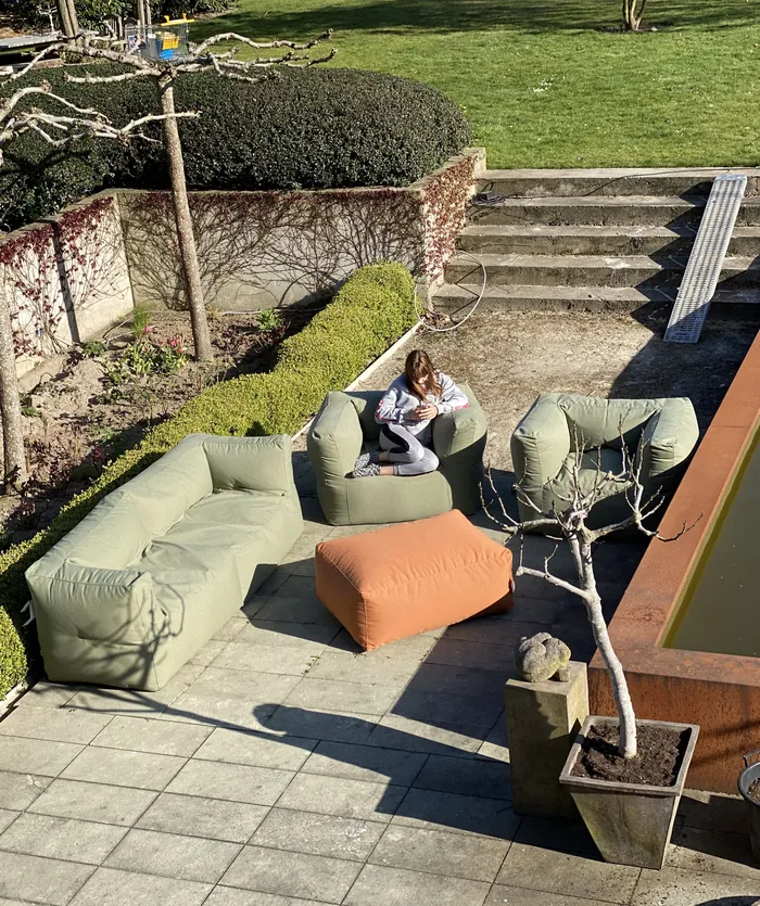 BRYCK loungeset met zachtgroene zitelementen en een oranje poef op een terras