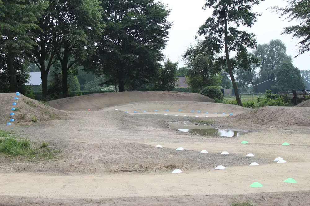 Aangelegde crossbaan met heuvels en bochten in een groen landschap