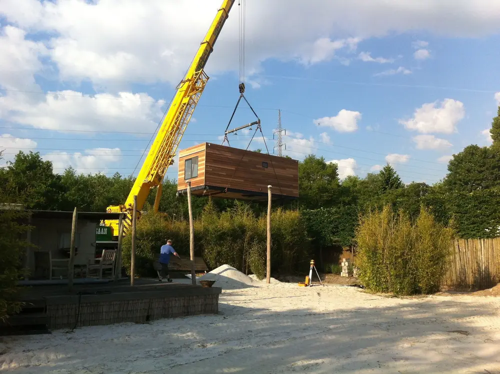 Gele hijskraan tilt een bouwdeel op zijn plek tijdens een groenproject
