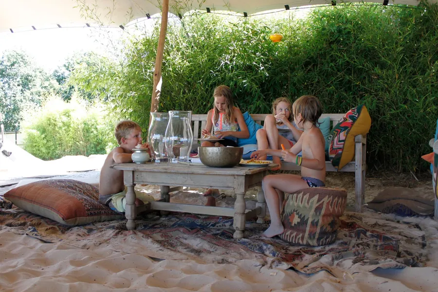Gezelschap aan een lage tafel in het zand op een zomerse dag